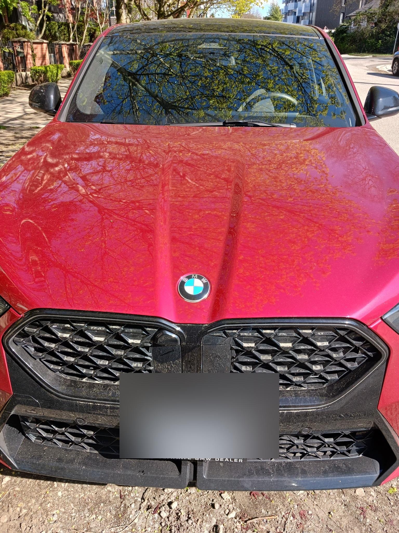 Front view of a red BMW vehicle with dual mesh grilles and blue BMW logo displayed outdoors